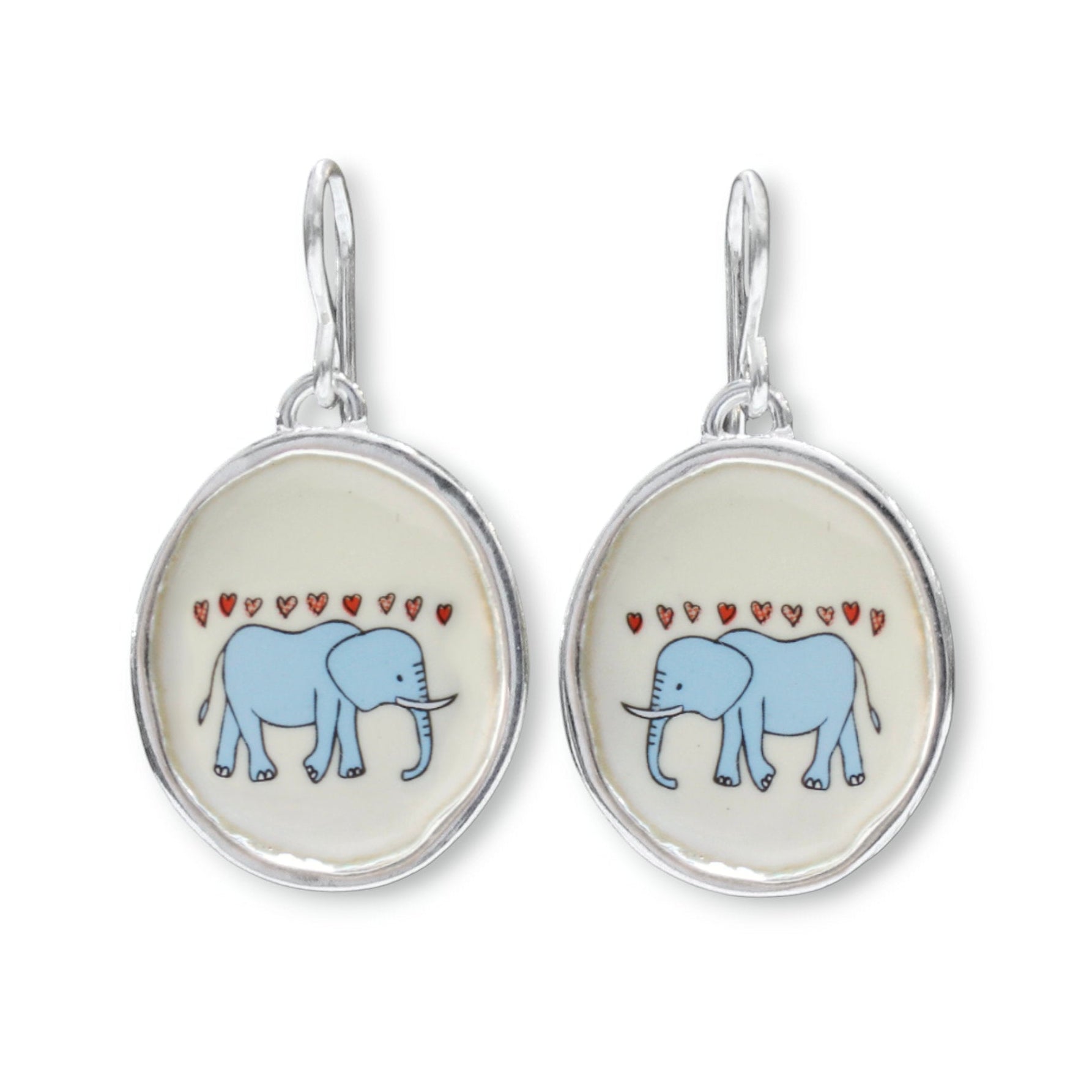 A pair of silver drop earrings featuring oval charms with a light blue elephant and small red hearts on a cream background.