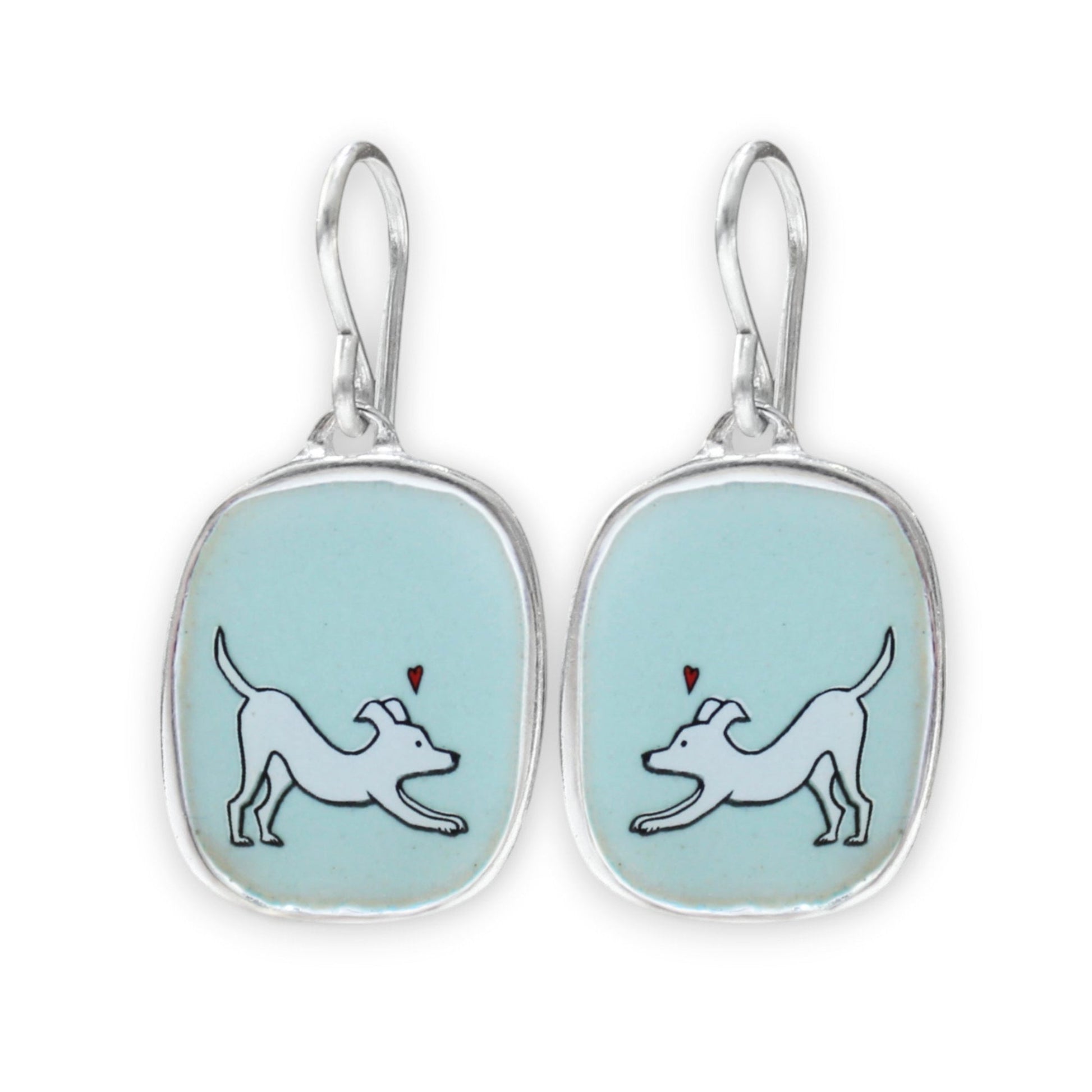 A pair of silver drop earrings with rounded rectangular bezel settings containing a light blue enamel background. Each earring features a white line-art illustration of a dog with a small red heart above it.