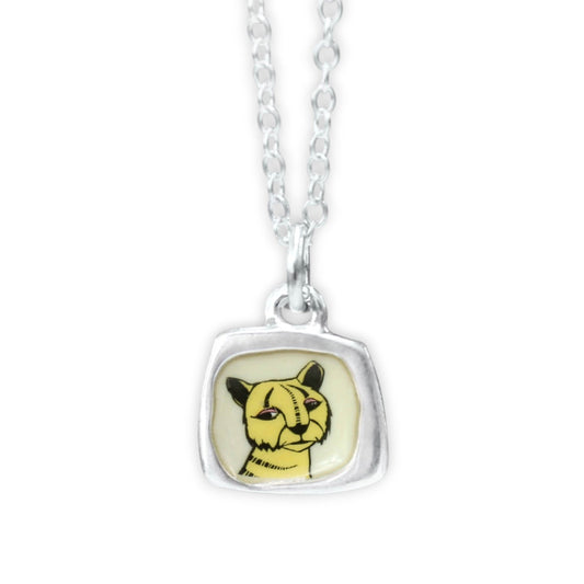A silver chain necklace with a square bezel pendant featuring a yellow and black cat illustration on a cream background.